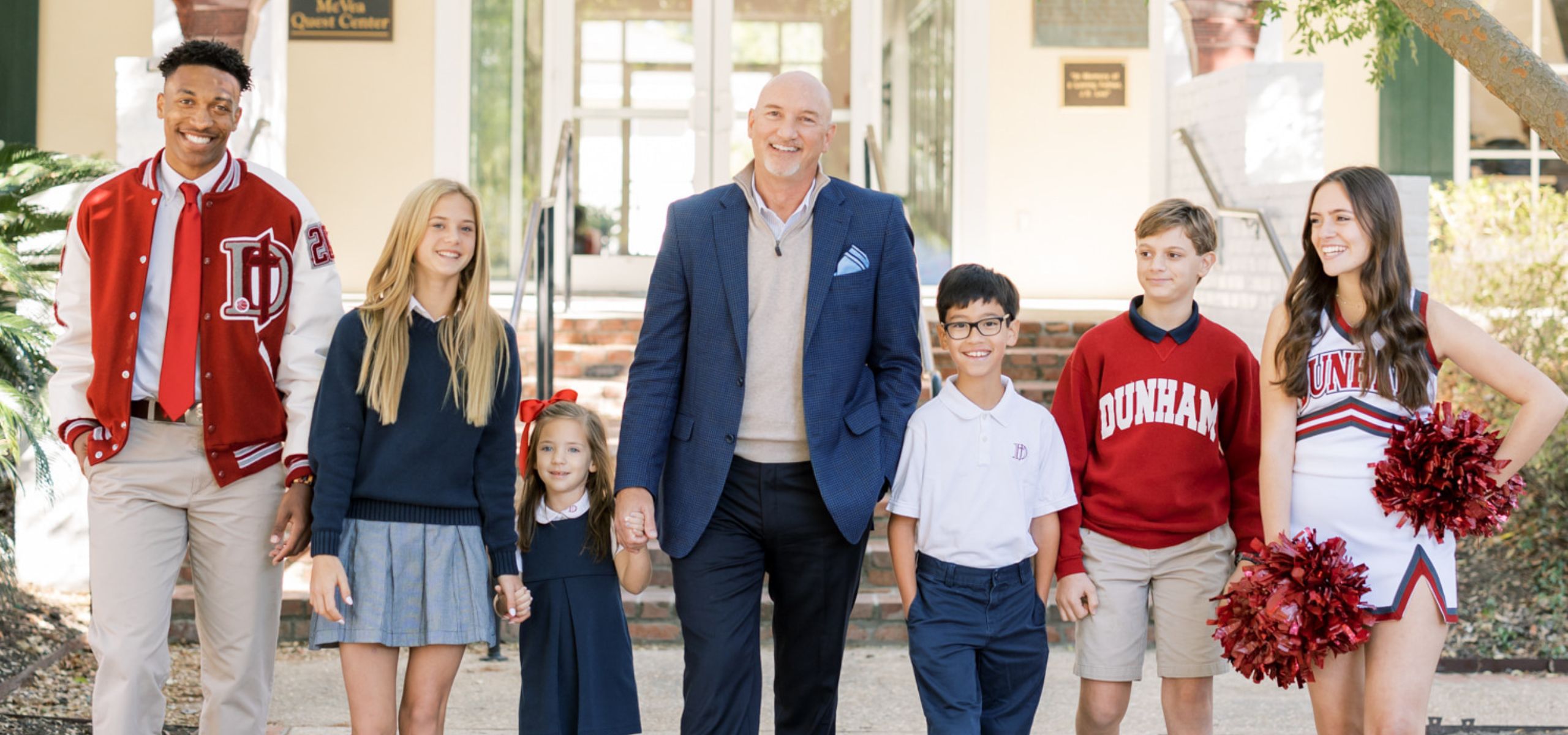 A photo of the Head of School walking with six students of different ages.